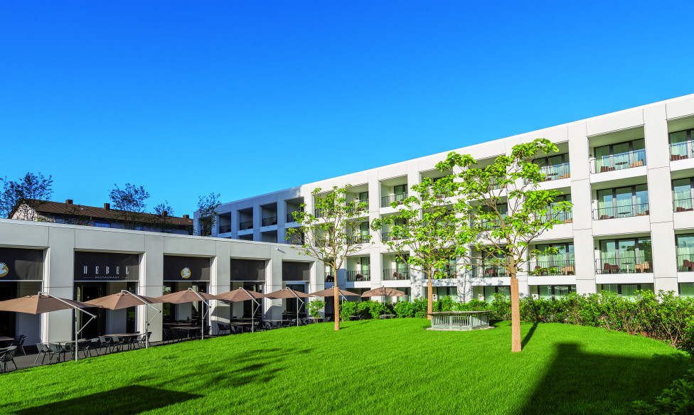 Der grüne Innenhof des Hotel Stadt Lörrach mit Blick auf das Restaurant Hebel und das Boardinghouse