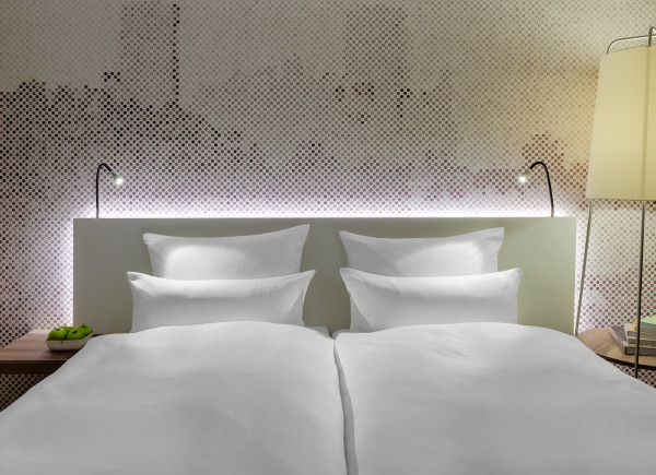 Blick auf das bequeme Bett mit weißer Bettwäsche und einem modern gestalteten Bild der Burg hinter dem Kopfteil
