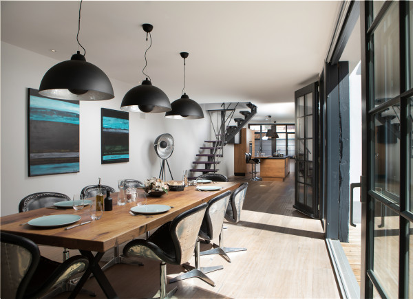 Blick in den Wohnbereich mit großem Esstisch und offener Küche. Stylische Lampen und eleganten Möbeln