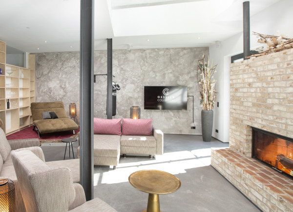 Blick in den WOhnzimmer-Bereich mit Sofas und Sesseln, offenem KAmin, einem Boxsack und TV